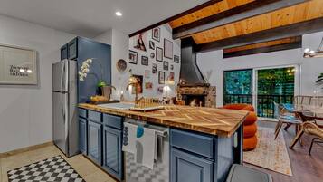 Una cocina moderna con una isla de madera, armarios azules y una chimenea de piedra.
