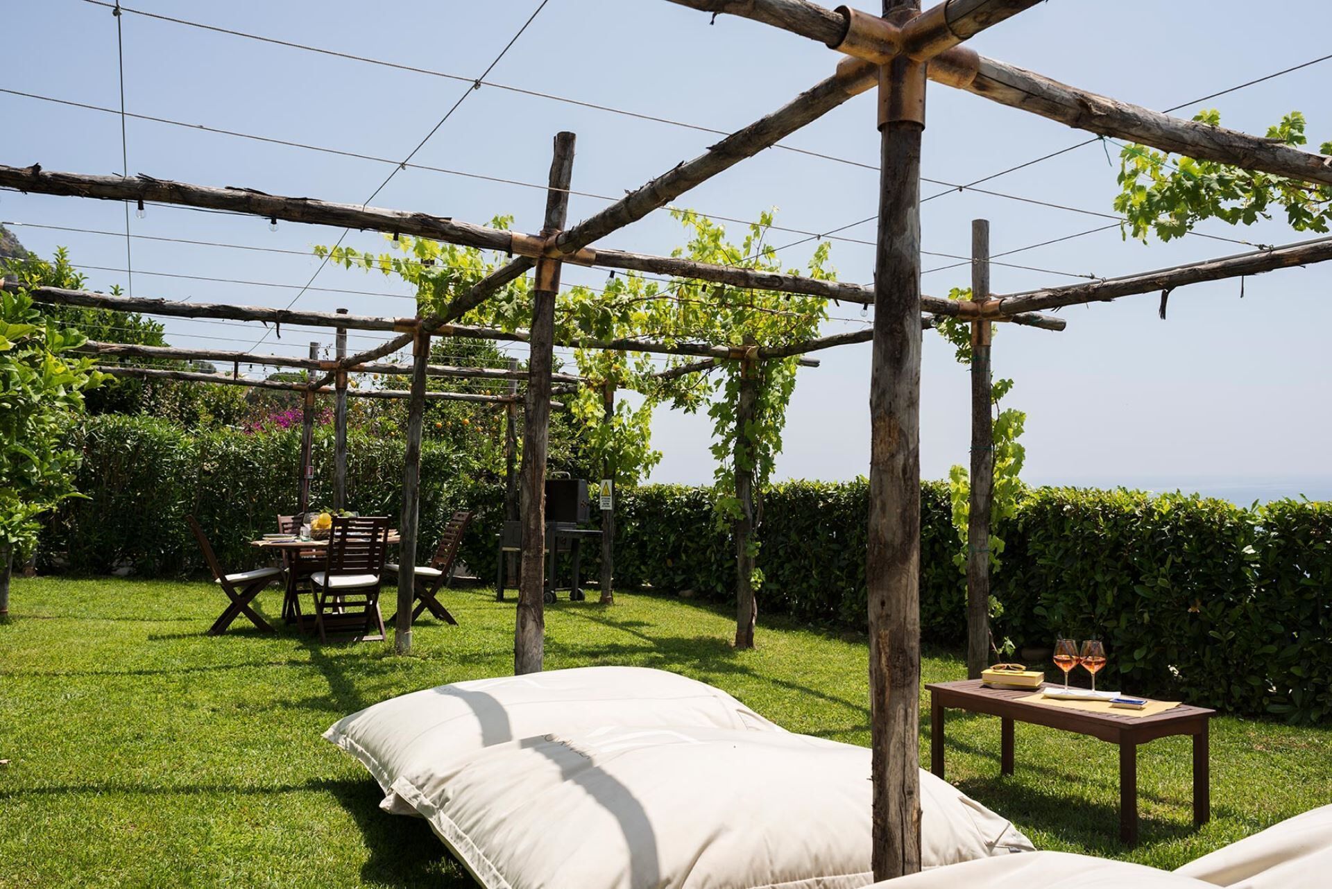 Ein Garten mit einer Pergola, einem Tisch mit Stühlen und einem Bett.