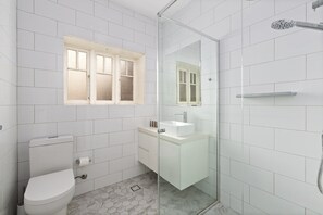 Een moderne badkamer met toilet, wastafel en douche.
