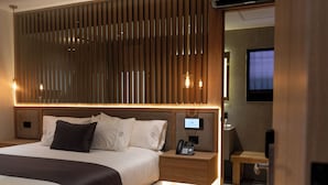 Una camera d'albergo moderna con un letto grande, un comodino con il telefono e una televisione nell'angolo.