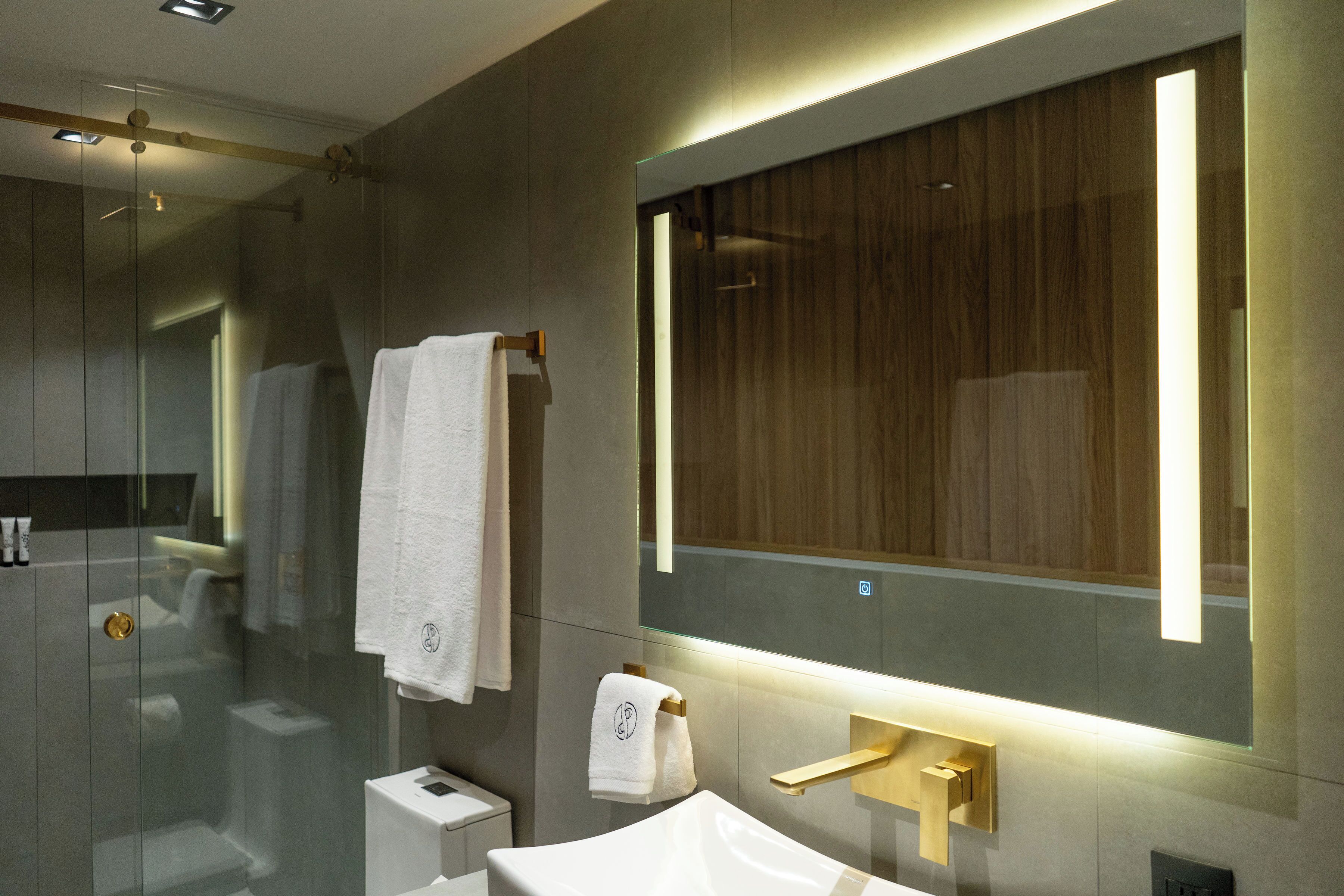 A modern bathroom with a glass shower enclosure, a large mirror, and a white sink.