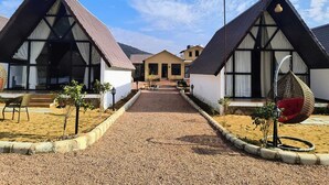A row of traditional-style cottages with pitched roofs, a gravel pathway, and a clear sky.