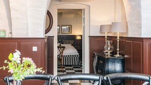 A hotel room with a checkered floor, a bed with striped bedding, a wooden dresser, and a lamp. - 4 Star Holiday Home in Skanderborg (Skanderborg)