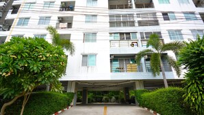 A multi-story building with a covered entrance, surrounded by greenery and a paved pathway. - Corner Studio With Balcony Near Jomtien Beach - Beach Mountain 6 (Pattaya)