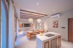 A modern kitchen with a central island, wooden dining table, and pendant lighting. - JamS Bali (Canggu)