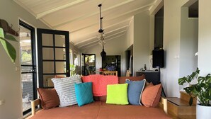 A cozy living room with a brown sofa, colorful cushions, a wooden coffee table, and a patterned rug.