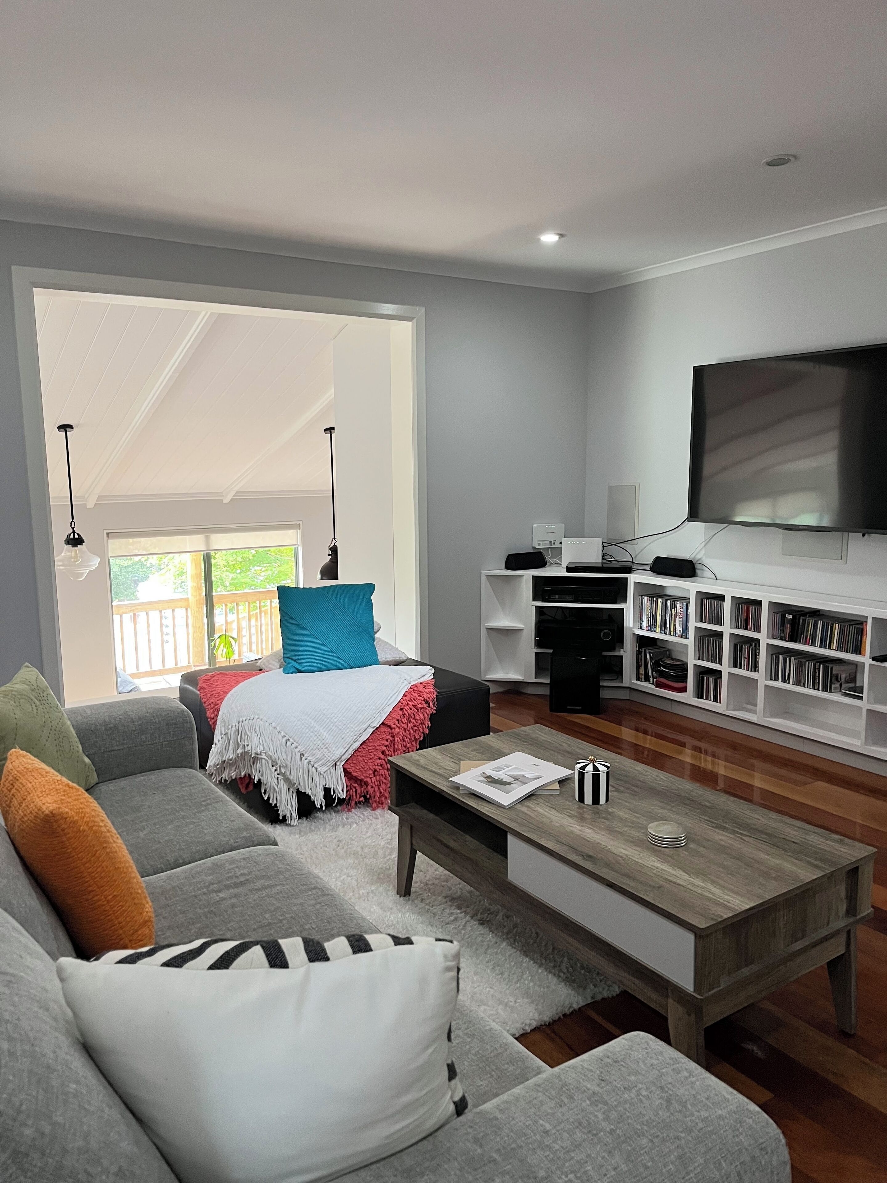 A modern living room with a grey sofa, a coffee table, and a bookshelf.