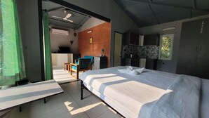 A modern hotel room with a large bed, a desk, and a kitchenette.