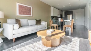 Een moderne woonkamer met een bank, salontafel en stoelen. Achtergrond is een keukenhoek.