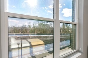 A window with a view of a snowy outdoor area, including a bench and a railing. - Blueground | Chevy Chase, rooftop, nr Glenview Park (Chevy Chase)