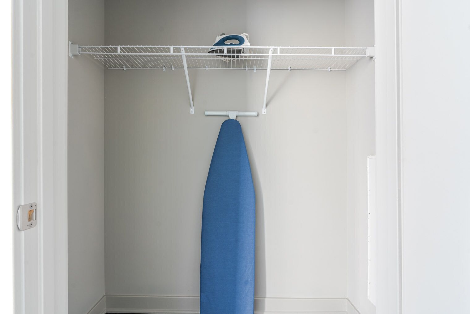 A closet with a hanging rack and an ironing board.
