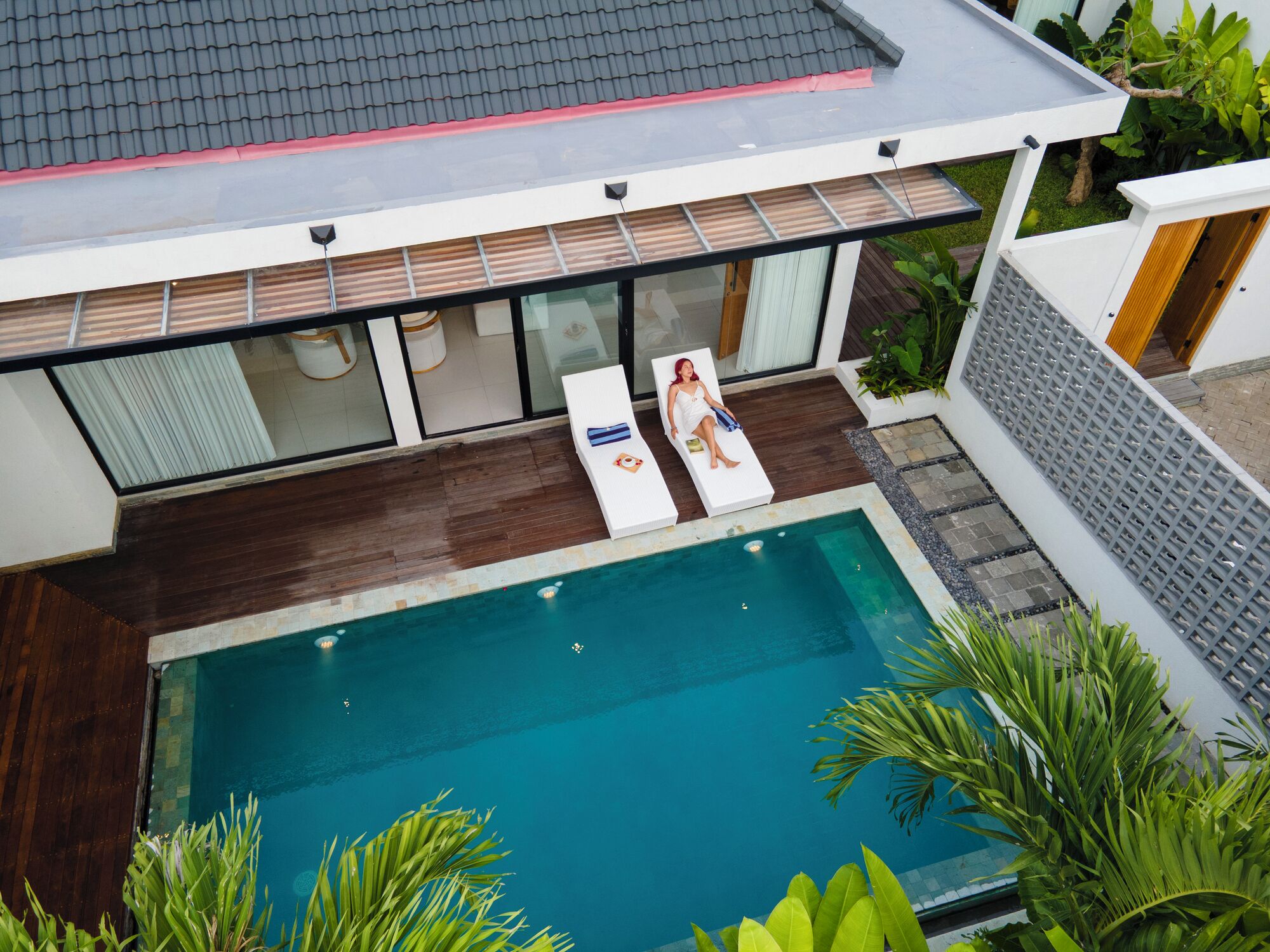 Ein modernes Haus mit Schwimmbad, zwei Liegestühlen und einer Holzterrasse.