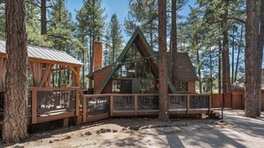 A cabin with a triangular roof, surrounded by trees.