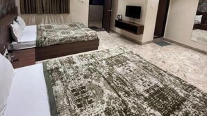 Una habitación de hotel moderna con dos camas, ventilador de techo, iluminación empotrada, televisor de pantalla plana y un ventanal con cortinas.