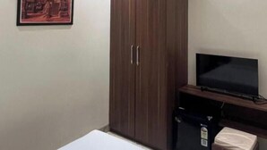 Un dormitorio con cama, armario, televisor, equipo de aire acondicionado y ventilador de techo.