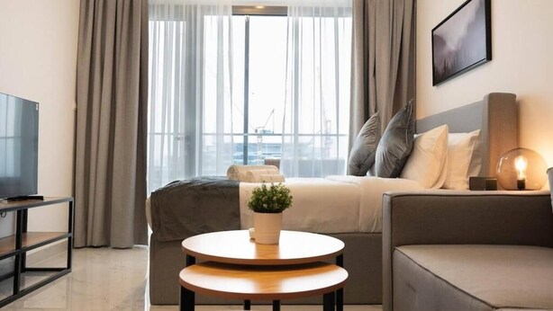Une chambre d’hôtel moderne équipée d’un lit, d’un canapé, d’une télévision et d’une petite table agrémentée d’une plante.