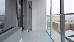 Un appartement moderne doté d’un balcon, de grandes fenêtres et offrant une vue sur le paysage urbain.