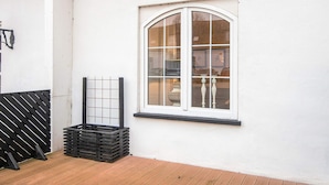 A white building with a large arched window, a black metal gate, and a stack of black crates. - 4 Star Holiday Home in Skanderborg (Skanderborg)