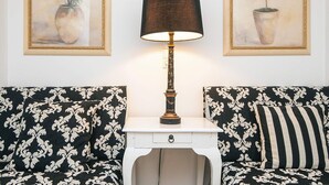 A room with a white table lamp, two framed paintings of potted plants, and a black and white patterned sofa. - 4 Star Holiday Home in Skanderborg (Skanderborg)