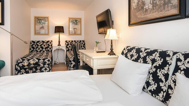 A hotel room with a bed, two chairs, a desk, a TV, and a painting on the wall. - 4 Star Holiday Home in Skanderborg (Skanderborg)