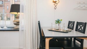 A dining area with a table set for four, a wall-mounted light fixture, and a view of a brick building through a window. - 4 Star Holiday Home in Skanderborg (Skanderborg)