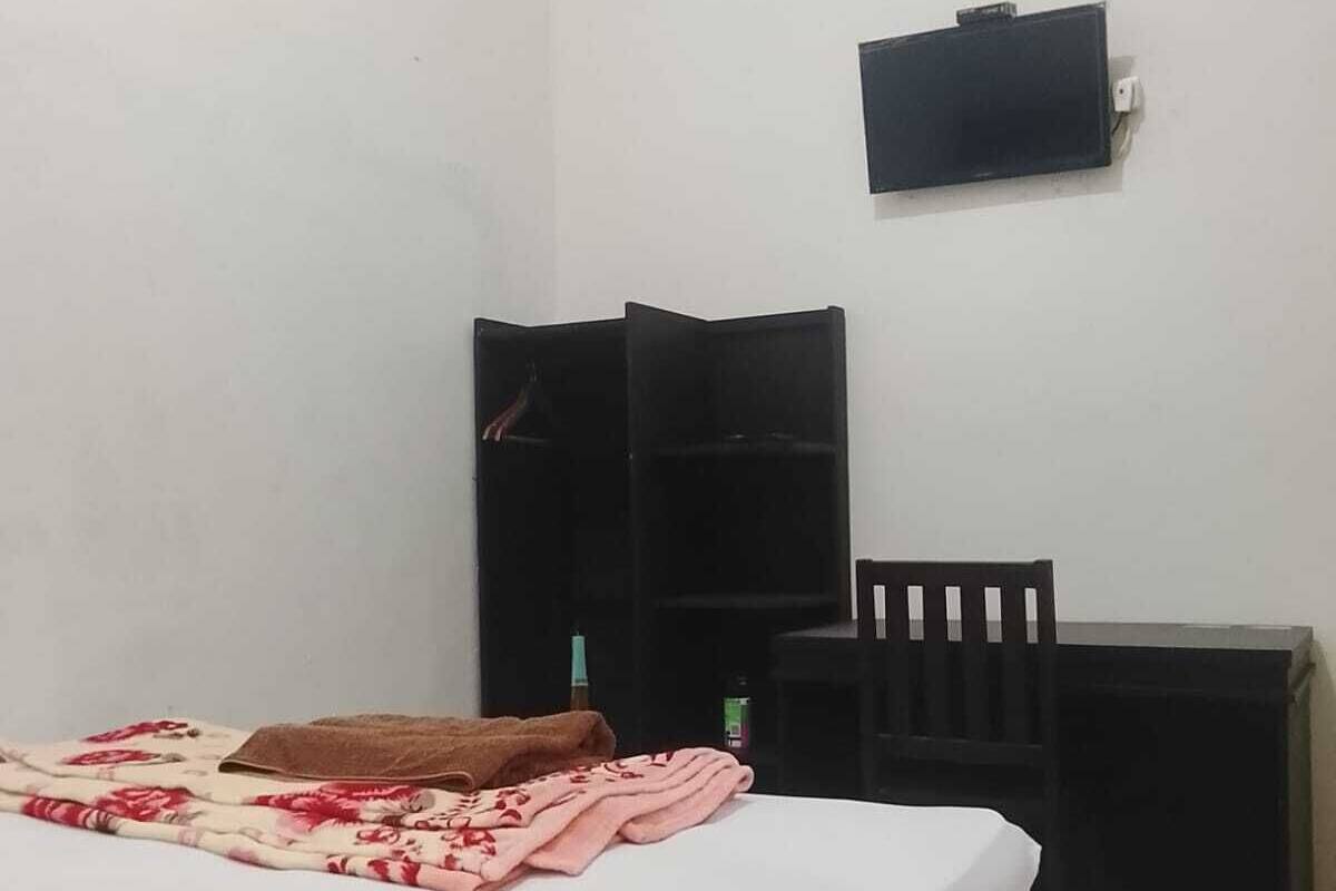 A bedroom with a bed, a desk, and a chair.