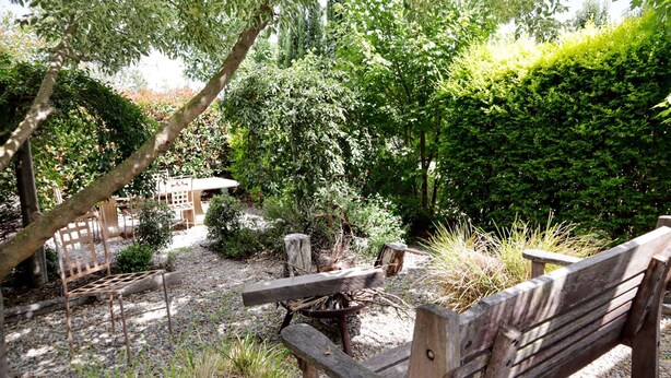 Un jardín con bancos de madera y un hogar rústico.