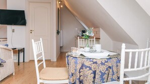 Een gezellige kamer met een eettafel, stoelen, een aan de muur bevestigde televisie en een deur.