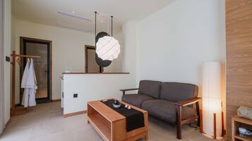 A modern living room with a sofa, a wooden coffee table, a hanging light fixture, and a standing lamp.