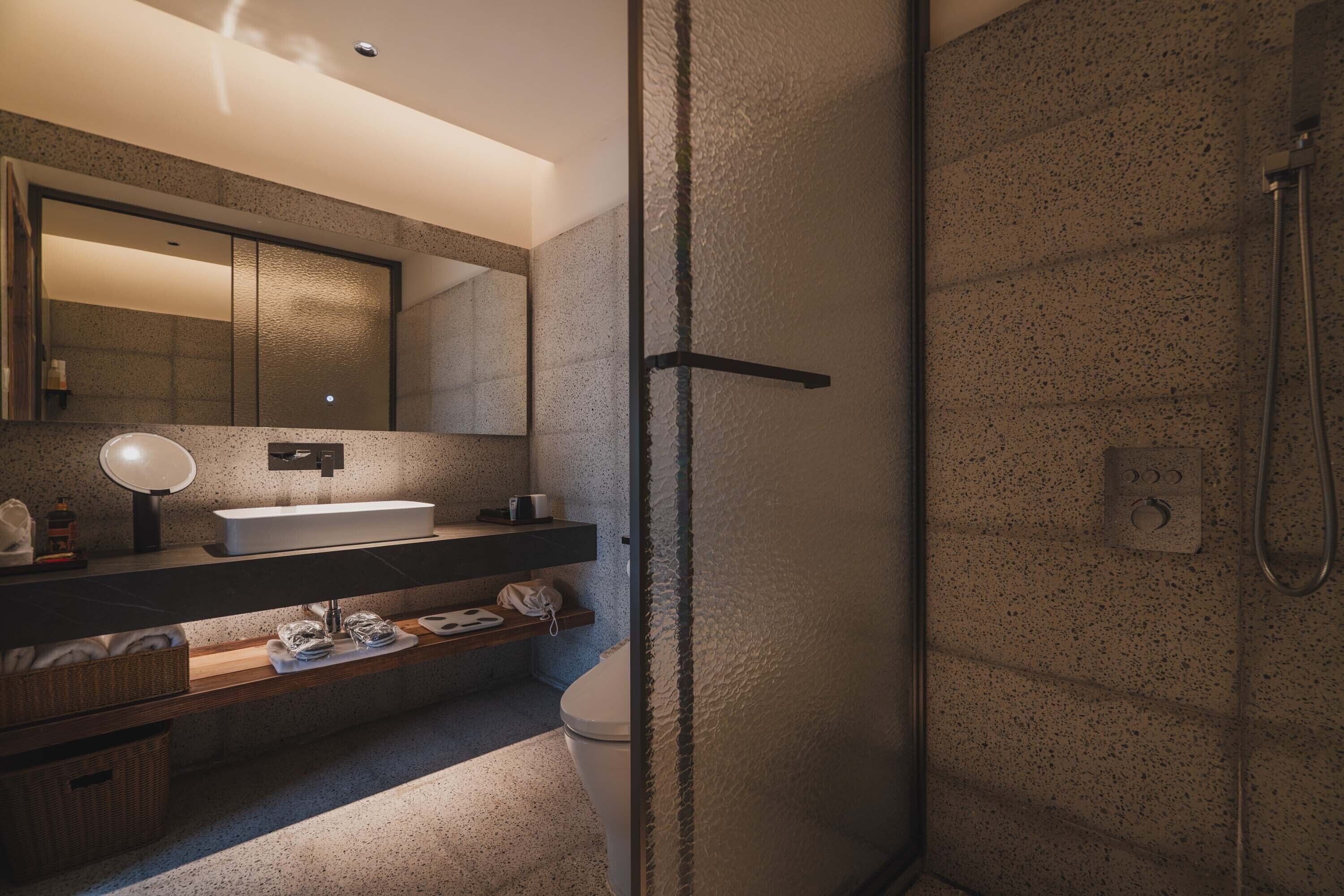 A modern bathroom with a freestanding shower, a large mirror, and a built-in sink.