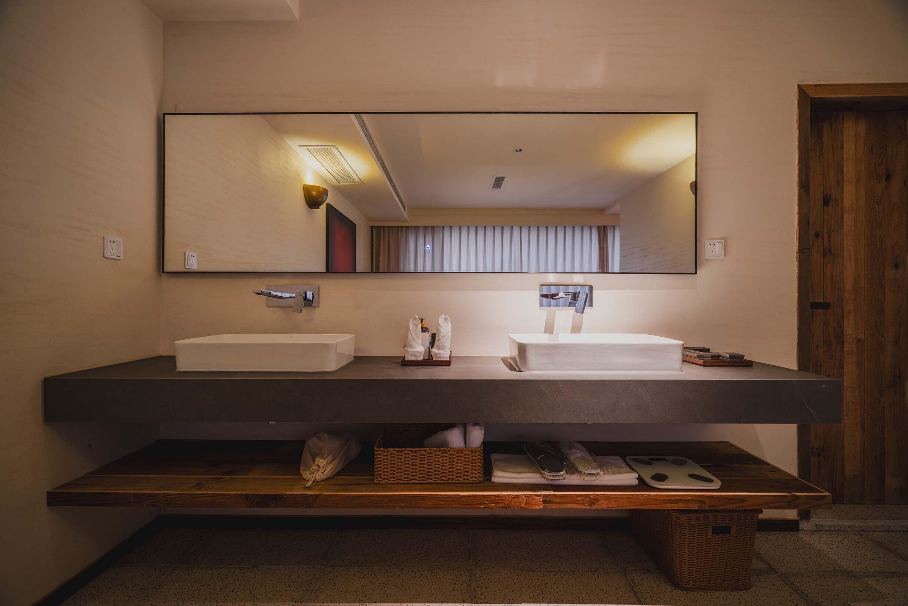 Un baño moderno con dos lavamanos, un espejo grande y un mueble de tocador de madera.