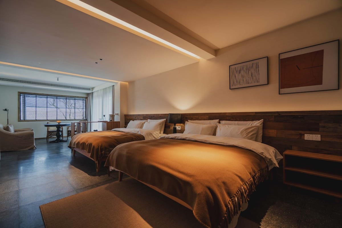 Una habitación de hotel moderna con dos camas, un escritorio y un ventanal grande.