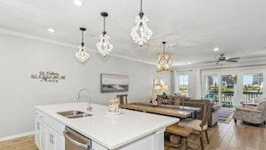 A modern kitchen with a central island, pendant lighting, and a dining area with a view of the outdoors. - New Listing! Lost Key Private Beach Club| 2 Swimming pools| Free Golf| Tennis| Bikes (Pensacola)