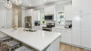 A modern kitchen with white cabinetry, stainless steel appliances, and a central island with bar stools. - New Listing! Lost Key Private Beach Club| 2 Swimming pools| Free Golf| Tennis| Bikes (Pensacola)