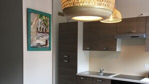 Eine moderne Küche mit dunklen Holzschränken, einer weißen Arbeitsplatte und einer hängenden Lampenschirm aus Bändern.