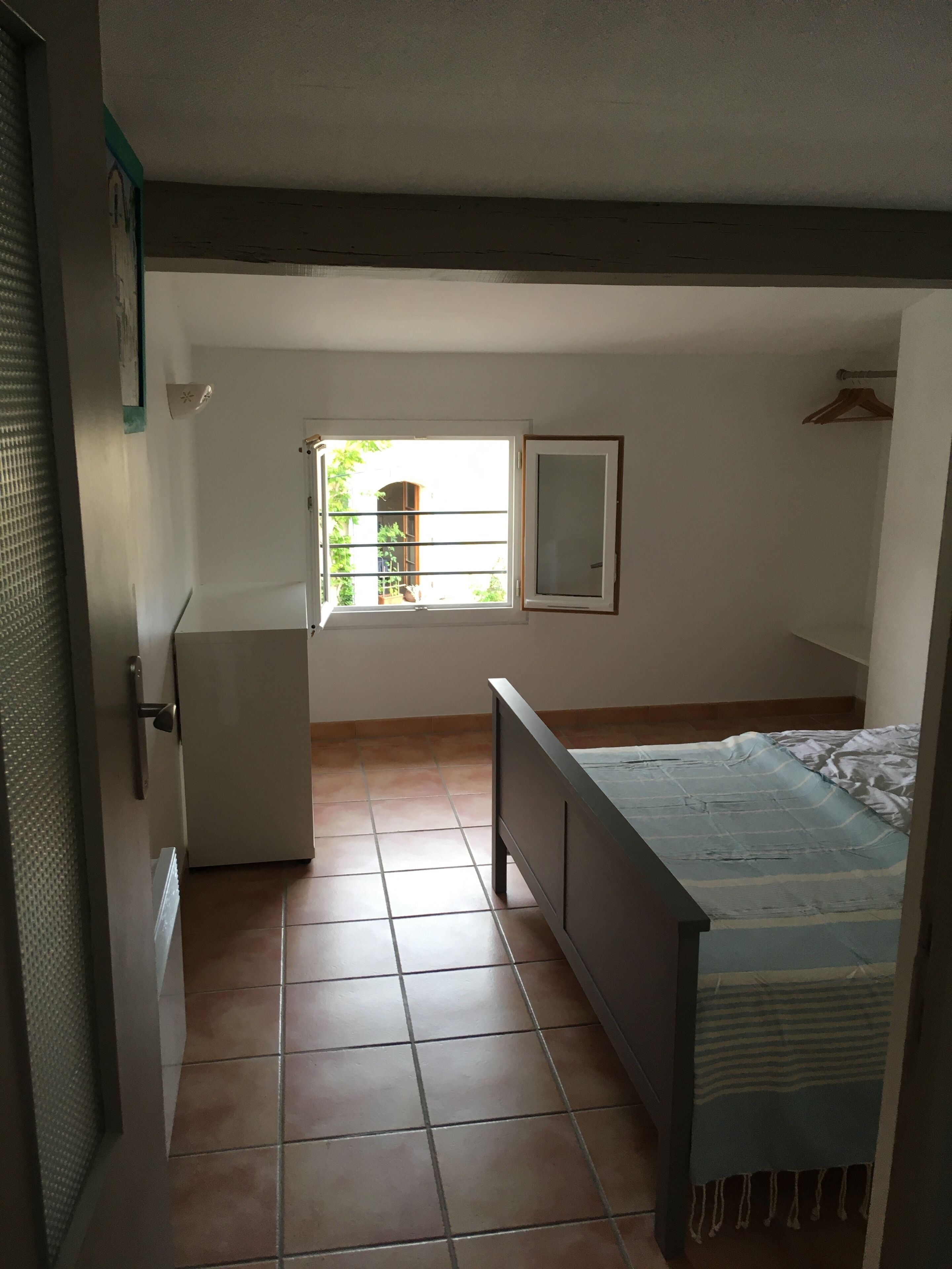 Una camera da letto con un letto, una finestra, un armadio e una porta.