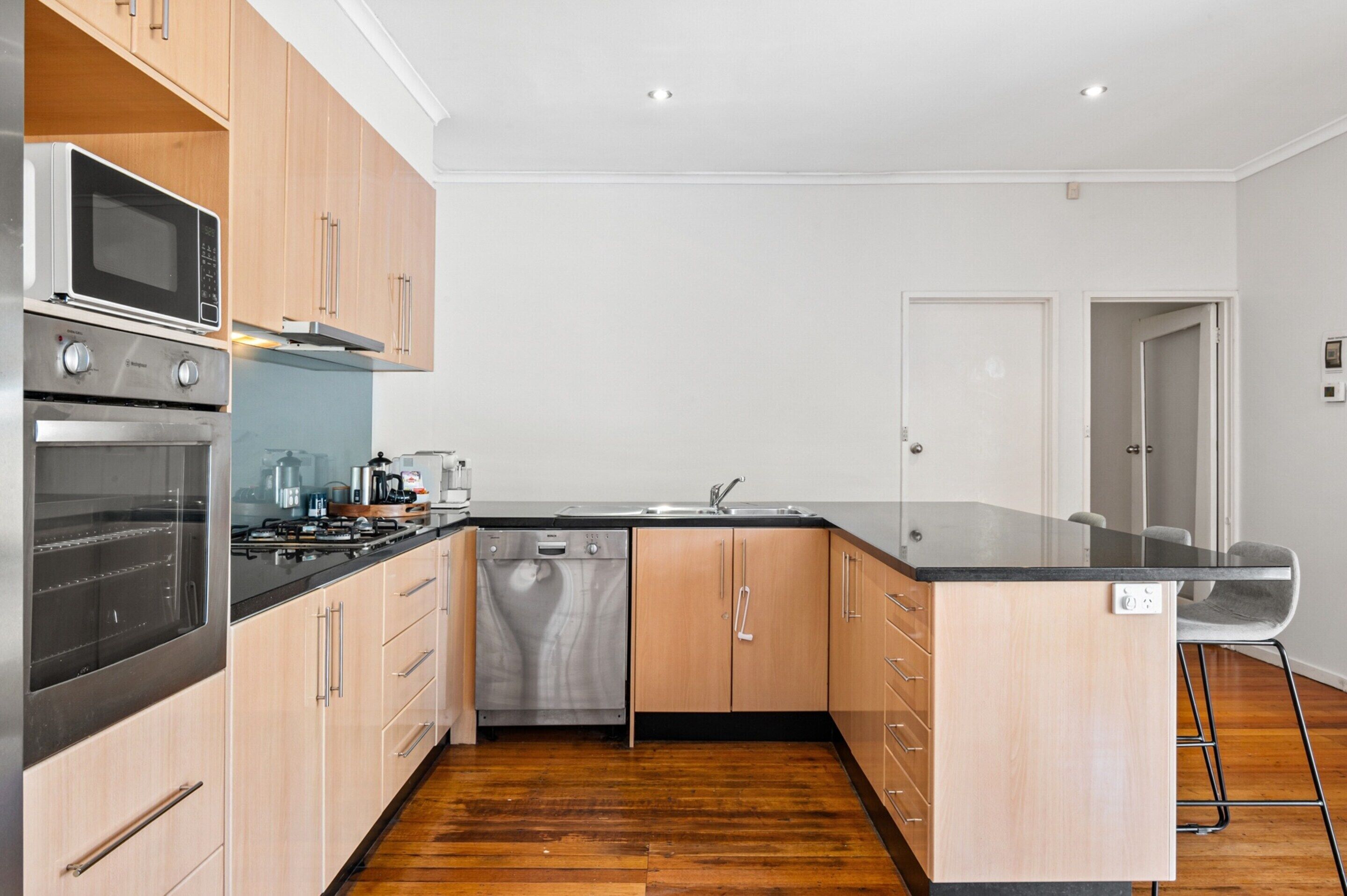 A modern kitchen with wooden cabinets, stainless steel appliances, and a black countertop.