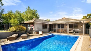 A swimming pool with lounge chairs and a covered patio area. - Spacious 5-bed Home With Pool in Glen Iris (Melbourne)