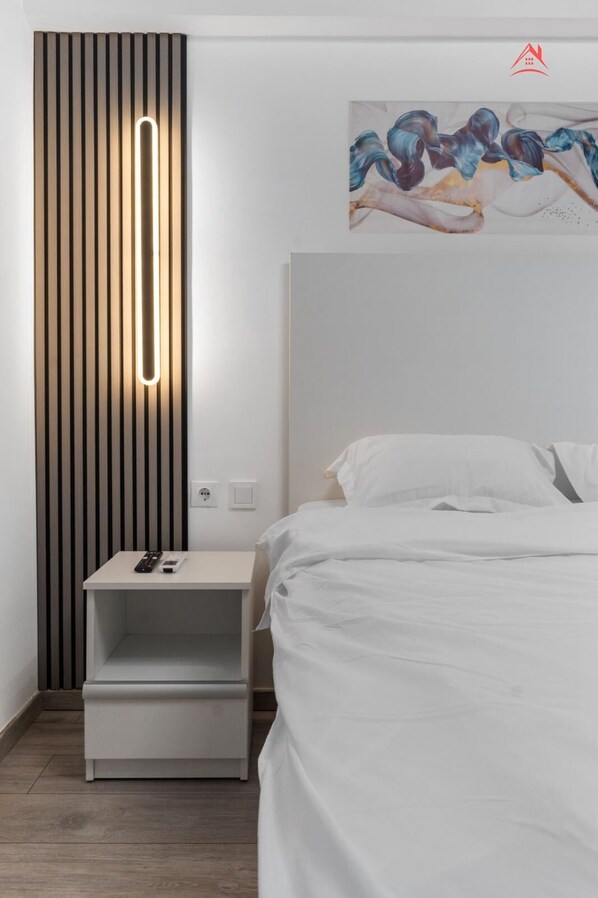 A modern bedroom with a bed, bedside table, and a wall-mounted light fixture. - Apartament Lucas București (Bucharest)
