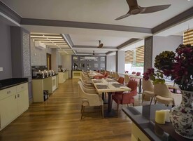Un comedor moderno con una mesa larga, sillas y una cocina al fondo.