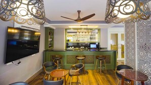 A bar area with a green counter, multiple bar stools, and a ceiling fan. - Meto Pema Hotel  (Phuntsholing)