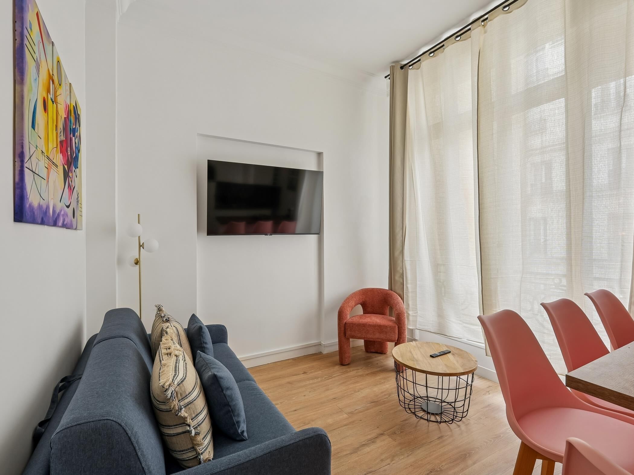 A modern living room with a grey sofa, a round coffee table, and a TV mounted on the wall.