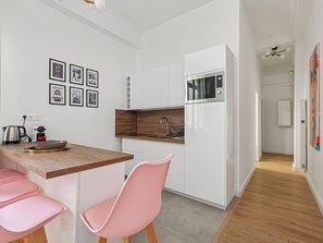Eine moderne Küche mit weißen Schränken, einer Holz Arbeitsplatte und einem pinkfarbenen Stuhl.