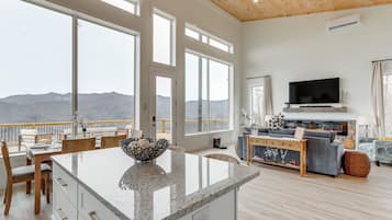 A spacious living area with a large window overlooking mountains, a kitchen island, and a cozy seating area.