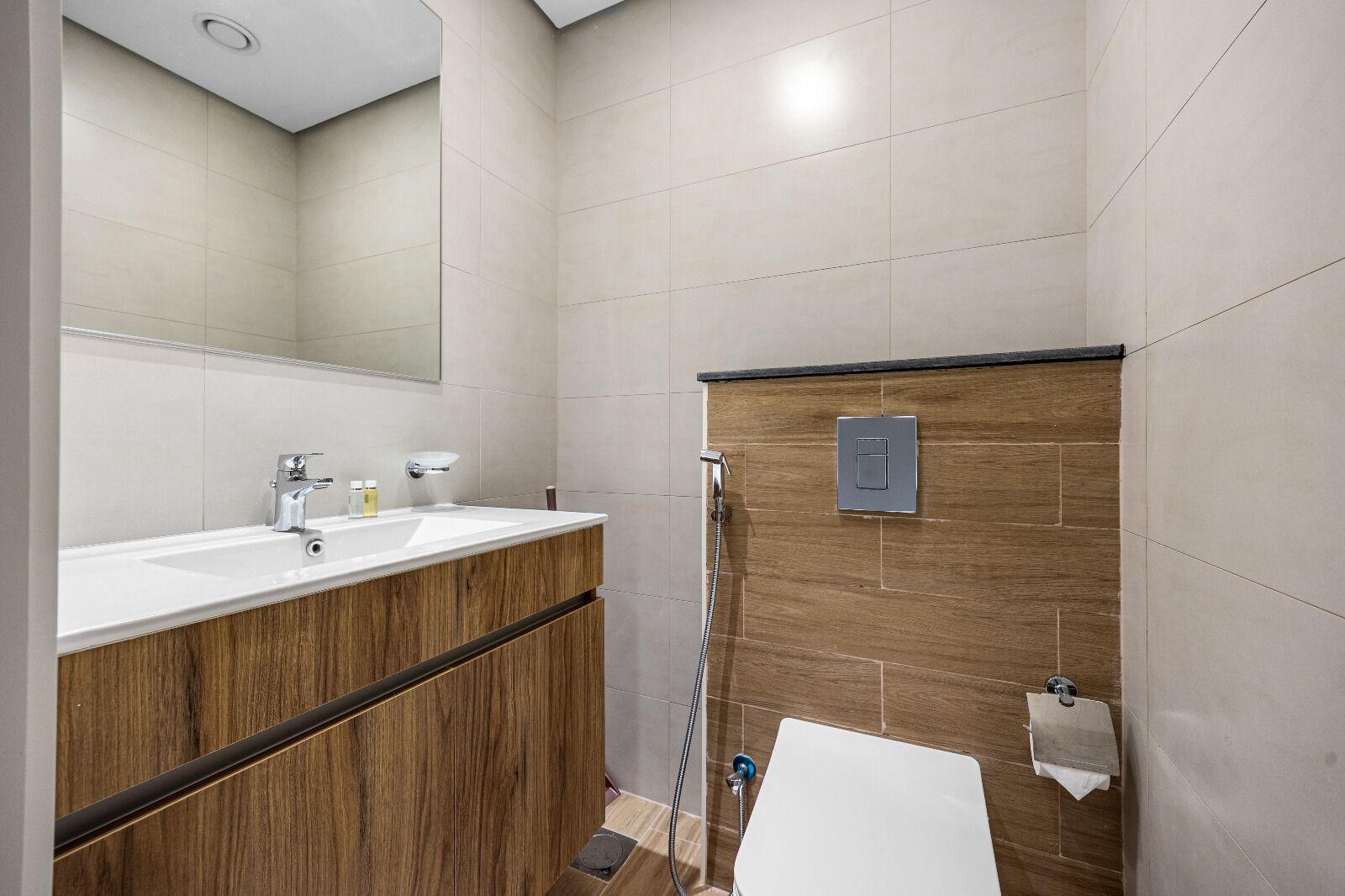 Ein modernes Badezimmer mit einem Holzbadschränkchen, einem großen Spiegel, einer Duschkabine und einer weißen Badewanne.