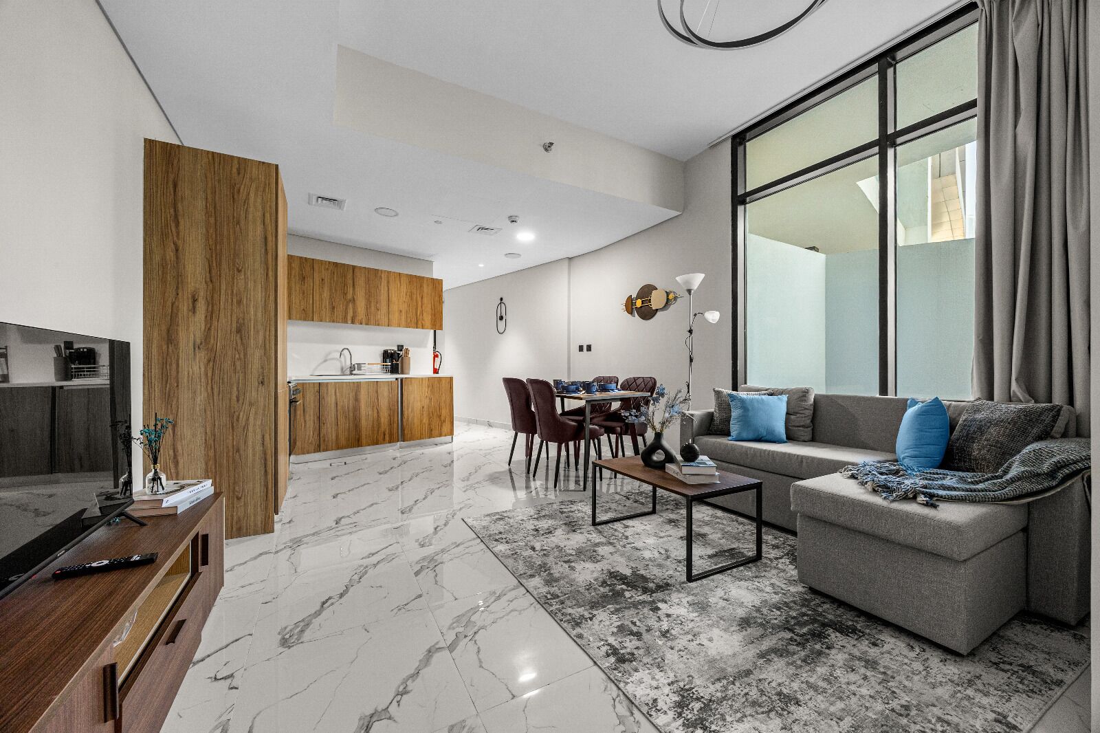Un salon moderne avec un canapé gris, une table basse et un coin repas comprenant des chaises et une table.