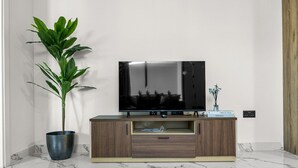 Ein modernes Wohnzimmer mit Flachbildfernseher auf einer Holzkommode, einem Blumentopf und einem Marmorboden.