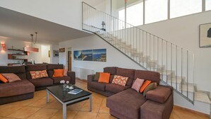 Un amplio salón con una escalera moderna, asientos cómodos y obras de arte en las paredes.