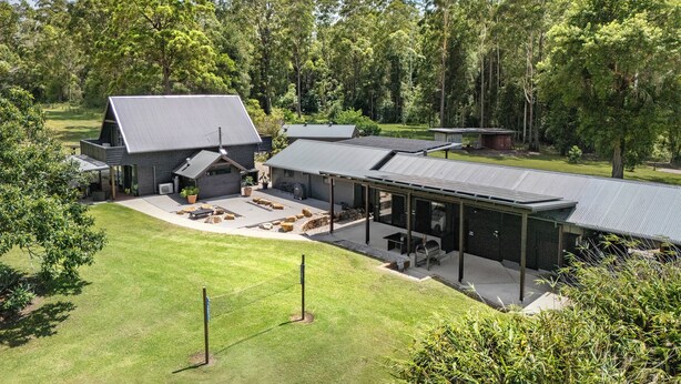 Een modern huis met een groot terras, een overdekt buitengebied en een verzorgd gazon.