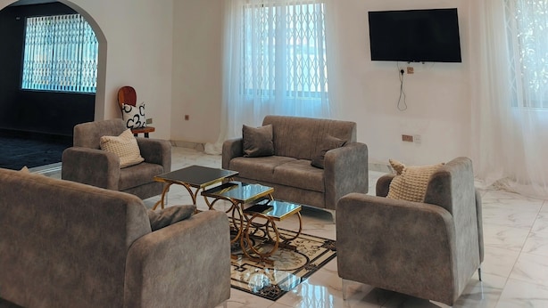 Un salón amplio con techo alto, televisor grande y chimenea.